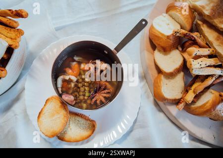 Suppe aus Meeresprodukten und Brotbackwaren auf weißem Hintergrund Stockfoto