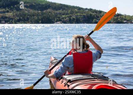 Frau im Kajak, Rückansicht. Glückliche junge Frau, die im transparenten Kajak auf dem kristallklaren Meer schwimmt. Sommerferien und fröhliche Frauen Stockfoto