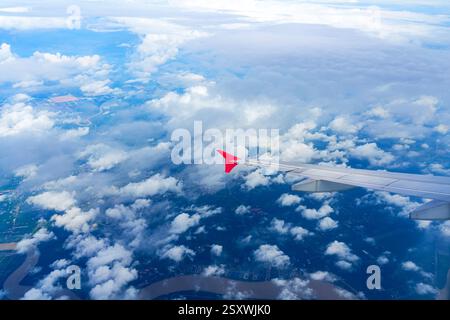 Flauschige Wolken, die durch das Fenster eines Flugzeugs gesehen werden. Blick vom Flugzeugfenster auf einen wunderschönen bewölkten Himmel und den Flugzeugflügel. Stockfoto