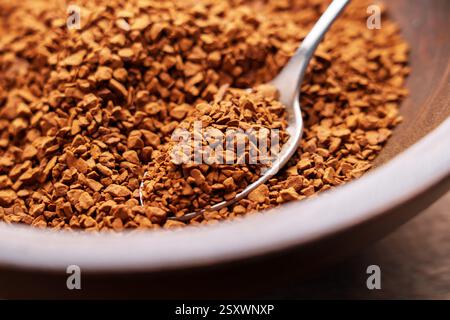 Metalllöffel Instantkaffee-Granulat. Geröstete biologisch lösliche Zutat eines aromatischen traditionellen Getränks in einer Holzschale. Energieschub und Erfrischung Stockfoto