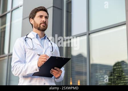 Gut aussehender männlicher Arzt in einem Labormantel mit einer Verschreibungsliste Stockfoto
