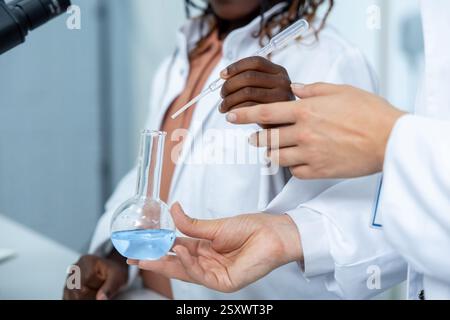 Verschiedene Forscher im Labor halten Reagenzröhrchen und analysieren Flüssigkeitsproben Stockfoto