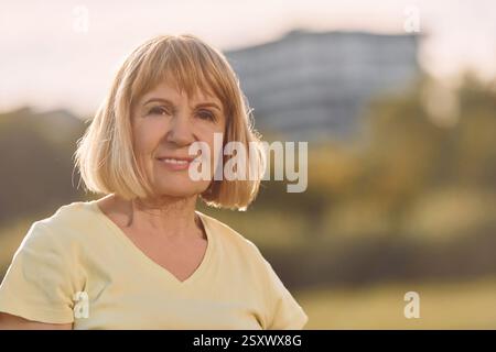 Porträt einer glücklichen Seniorin, die ein schönes Wochenende draußen auf dem Feld an sonnigen Tagen hat. Stockfoto
