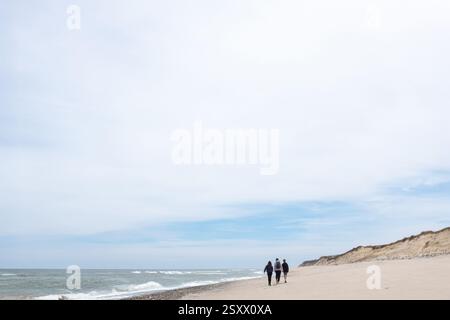 Familienspaziergang an einem ruhigen Strand an einem klaren, friedlichen Tag Stockfoto