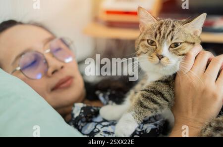 Schöne reife glückliche lächelnde Frau mit einer Katze in den Armen im Wohnzimmer zu Hause. Selektiver Fokus. Stockfoto