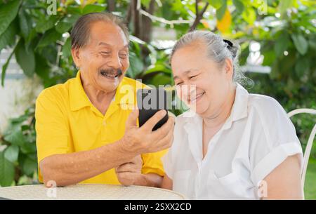 Zwei alte und ältere Leute zu Hause, die gemeinsam im Garten telefonieren. Glückliches Familienkonzept. Selektiver Fokus. Stockfoto