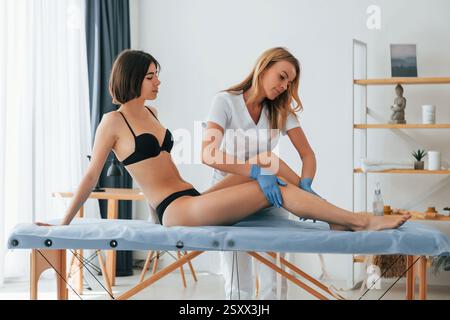 Arbeiten mit Beinen. Frau wird in der Klinik von einer Ärztin mit Zucker behandelt. Stockfoto