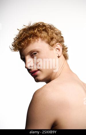Ein junger, gutaussehender Mann mit lockigem Ingwerhaar zeigt einen trendigen Look und strahlt Selbstvertrauen aus. Stockfoto