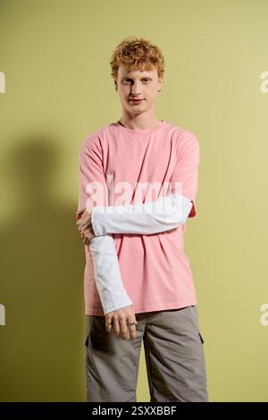 Ein modischer junger Mann strahlt Charme aus, während er ein stilvolles pinkfarbenes Hemd und eine leichte Hose trägt. Stockfoto