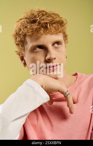 Ein junger Mann mit lockigen Haaren zeigt seinen trendigen Stil in einer bunten Umgebung. Stockfoto