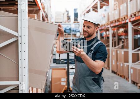 Aktivieren des Kontrollkästchens. Mitarbeiter in Uniform arbeitet tagsüber im Lager. Stockfoto