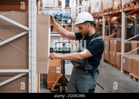 Aktivieren des Kontrollkästchens. Mitarbeiter in Uniform arbeitet tagsüber im Lager. Stockfoto