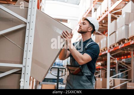 Nehmen Sie die Box heraus. Mitarbeiter in Uniform arbeitet tagsüber im Lager. Stockfoto