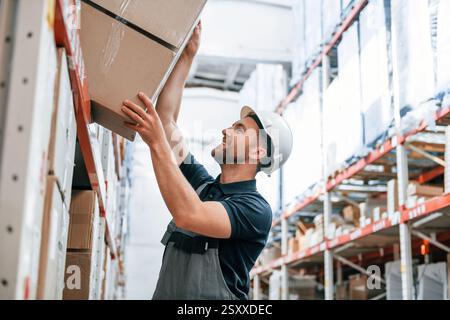Nehmen Sie die Box heraus. Mitarbeiter in Uniform arbeitet tagsüber im Lager. Stockfoto