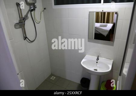 Billiges Hotelbad in Malaysia. Das Badezimmer ist im allgemeinen mit Waschbecken, Spiegel und Dusche ausgestattet. Stockfoto