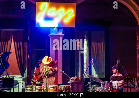 Sanlucar de Barrameda, Spanien, 17. Juli 2004, Jerry Gonzalez tritt mit Trompete und Percussion unter leuchtendem Neonlicht in einem Veranstaltungsort auf. Stockfoto