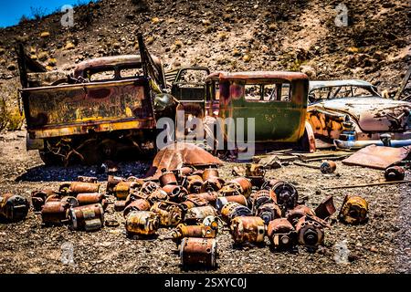 Stapel alter Autoteile und ein Fahrzeug, das gerade zerlegt wird. Die Autoteile sind in der Gegend verstreut Stockfoto