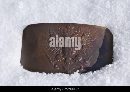 Nahaufnahme einer Gürtelschnalle der russischen Kaiserlichen Armee auf dem Schnee im Winter Stockfoto