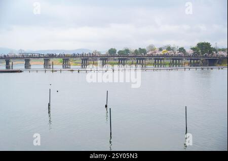 Touristen an der Togetsu-kyo-Brücke, einer Holzbrücke, die den Katsura-Fluss vor den Arashiyama-Bergen in Kyoto, Japan überspannt. Stockfoto