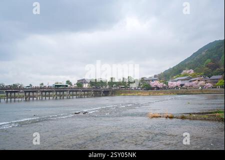 Touristen an der Togetsu-kyo-Brücke, einer Holzbrücke, die den Katsura-Fluss vor den Arashiyama-Bergen in Kyoto, Japan überspannt. Stockfoto