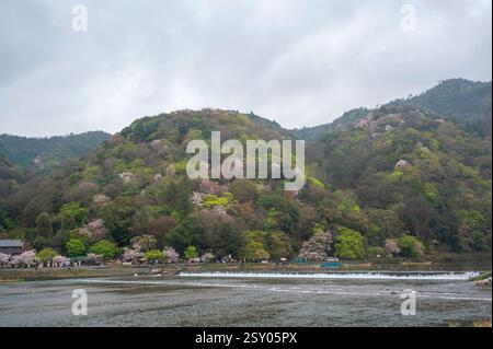 Touristen an der Togetsu-kyo-Brücke, einer Holzbrücke, die den Katsura-Fluss vor den Arashiyama-Bergen in Kyoto, Japan überspannt. Stockfoto