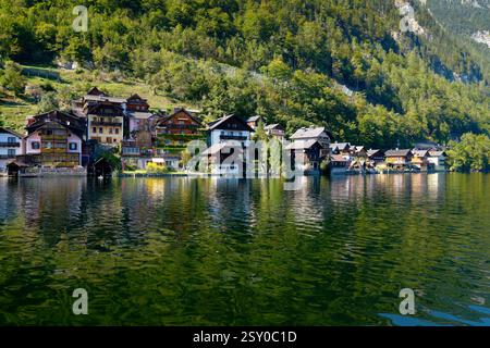 Traditionelle Häuser spiegeln sich im Hallstätter See wider. Häuser am Ufer des Hallstätter Sees bei Sonnenschein. Hallstatt, Österreich. Stockfoto