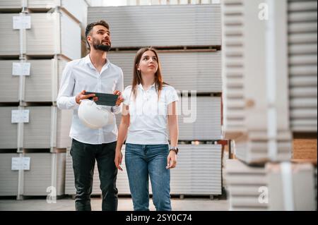 Der junge Manager in formeller Kleidung arbeitet mit der Frau im Lager. Stockfoto