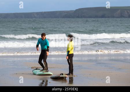 Ein Surflehrer der Escape Surfing School, der eine Surfstunde mit einem Anfänger am Towan Beach in Newquay Cornwall, Großbritannien, hält. Stockfoto