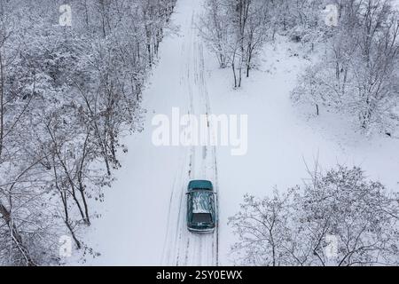 Aus der Vogelperspektive eines Autos, das auf vereister Straße im Wald fährt Stockfoto