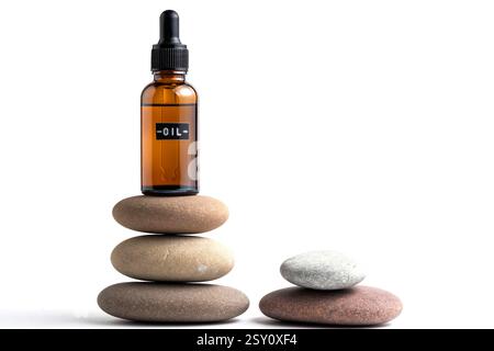 Ätherisches Öl in Glasflasche auf Kieselstapel Stockfoto