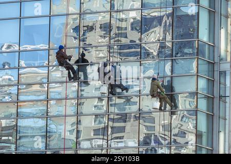 Almaty, Kasachstan - 21. Februar 2025: Arbeiter reinigen die Fassade eines Wolkenkratzers. Reinigungsfirma Stockfoto
