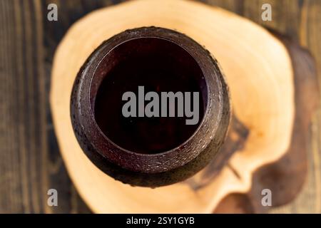 Trinken Sie in einem Glas auf einem Walnussbrett, Details des roten alkoholischen Getränks Wein in einem klaren Glas Stockfoto