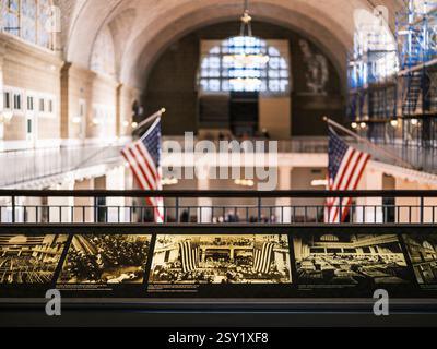 Blick von der obersten Etage von Ellis Island mit Informationstafeln, amerikanischen Flaggen, großer Architektur, einem Kronleuchter und Gerüsten während der Restaurierung. Stockfoto