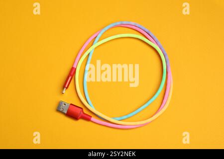 Ein USB-Ladekabel auf orangefarbenem Hintergrund, Draufsicht Stockfoto