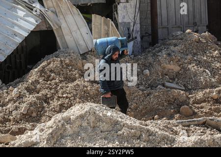 Tulkarm, Palästina. Februar 2025. Ein Palästinenser trägt seine Sachen, als er aus dem Flüchtlingslager Nour Shams flieht. Israelische Truppen erlaubten den Bewohnern, ihre Sachen zurückzuholen, nachdem sie Abrissanzeigen für mehrere Häuser ausgestellt hatten, während eines wochenlangen Angriffs auf das Westjordanland, bei dem rund 30.000 Palästinenser aus ihren Häusern innerhalb des nur Shams Flüchtlingslagers vertrieben wurden. Quelle: SOPA Images Limited/Alamy Live News Stockfoto