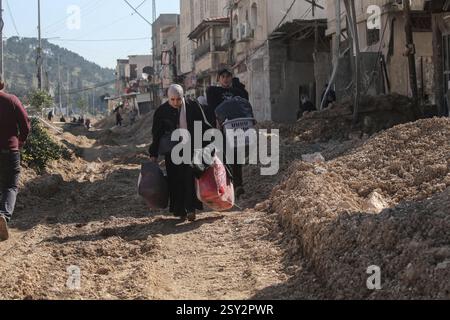 Tulkarm, Palästina. Februar 2025. Palästinensische Familien tragen ihre Sachen, als sie aus dem Flüchtlingslager Nour Shams fliehen. Israelische Truppen erlaubten den Bewohnern, ihre Sachen zurückzuholen, nachdem sie Abrissanzeigen für mehrere Häuser ausgestellt hatten, während eines wochenlangen Angriffs auf das Westjordanland, bei dem rund 30.000 Palästinenser aus ihren Häusern innerhalb des nur Shams Flüchtlingslagers vertrieben wurden. Quelle: SOPA Images Limited/Alamy Live News Stockfoto