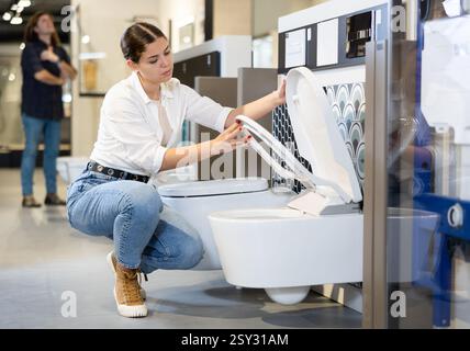 Weibliche Kundin, die sich weiße Toiletten im Verkauf in einem modernen Geschäft oder Einkaufszentrum ansieht Stockfoto