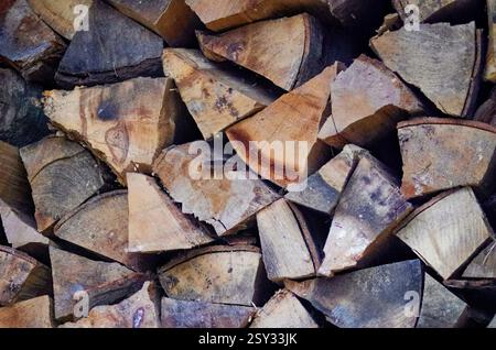 Eine detaillierte Ansicht des gehackten Brennholzes, das auf einem Stapel angeordnet ist und unregelmäßige Formen, Kornmuster, Knoten und natürliche Texturen im Holz zeigt. Stockfoto