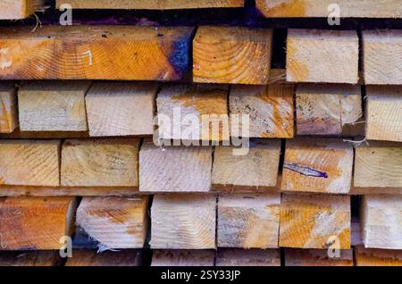 Die gestapelten Holzdielen sind gleichmäßig angeordnet und zeigen natürliche Kornmuster, Sägespuren, Knoten, Verfärbungen und eine Mischung aus hellen und dunklen Tönen. Stockfoto