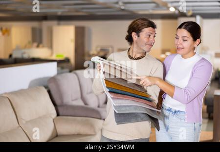 Der Mann präsentiert einer Frau Polstermuster Stockfoto