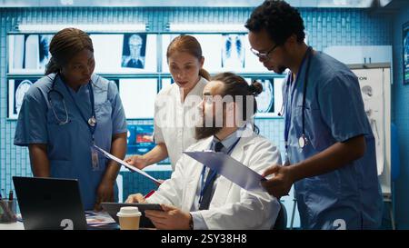 Medizinisches Team diskutiert Röntgenergebnisse und Patientenversorgungsstrategie in einem Behandlungszentrum, Expertise in Radiologie und Krankheitsprävention. Zusammenarbeit sichert Diagnose und Medizin. Kamera B.. Stockfoto