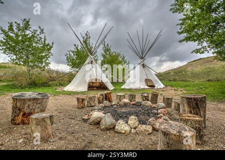Zwei Tipis sind mitten auf einem Feld. Es gibt eine Feuerstelle in der Mitte der Tipis Stockfoto