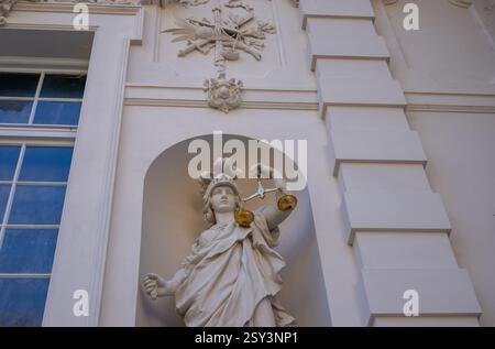 Eine Niedrigwinkelaufnahme des Linderhof-Schlosses auf Augenhöhe mit einer Atlas-Skulptur, die den Globus hält, umgeben von anderen Statuen und verzierten Statuen. Stockfoto