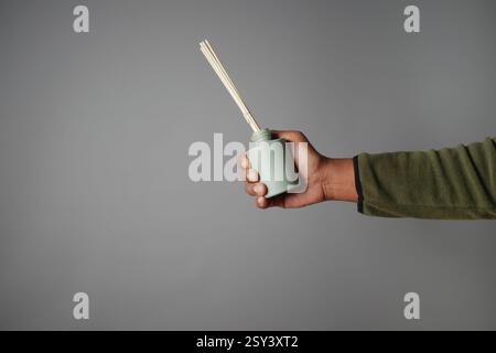 Die Hand hält einen grünen Diffusor mit Schilf für aromatischen Duft Stockfoto