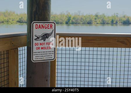 Weiter Blick über die Wood Observation Deck Kettenzaun des Naturpfads mit verschwommenem Wasser im Rücken. Rot, weiß und schwarz auf dem Schild auf der linken Seite steht „nicht F“ Stockfoto