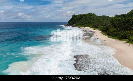Aus der Vogelperspektive auf eine Küste mit klarem blauem Meer und grünen Hügeln im Hintergrund. Strand Von Anse Bazarca. Seychellen, Mahe. Stockfoto