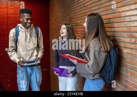 Glückliche Studenten, die sich im Flur der Universität unterhalten und lachen, genießen ihre Pausenzeit Stockfoto