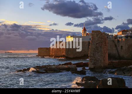 Ein atemberaubender Sonnenuntergang über den alten Mauern von Akko, Israel. Das goldene Licht hebt die historische Festung am Meer hervor, während die Wellen gegen die krachen Stockfoto