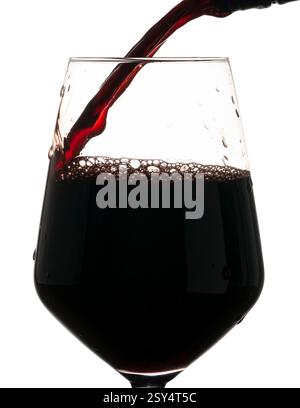 Rotwein wird in ein Weinglas gegossen. Gefrorene Flüssigkeitsbewegung auf weißem Hintergrund Stockfoto