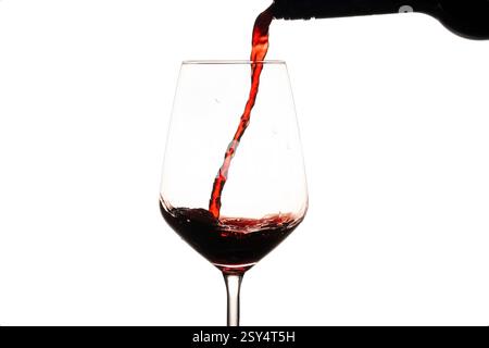 Rotwein wird in ein Weinglas gegossen. Gefrorene Flüssigkeitsbewegung auf weißem Hintergrund Stockfoto